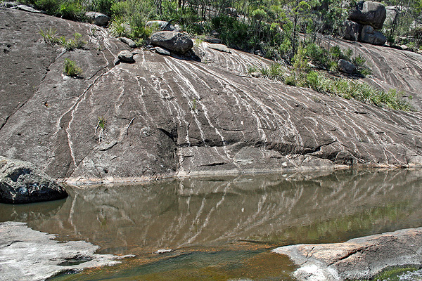 Like scale in a kettle the rivulets that run over the granite leave whitish deposits; reflected in the pool.