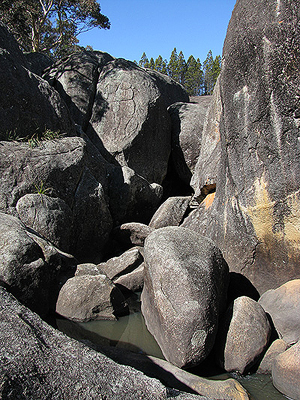 The creek is clearly visible before it disappears beneath the boulders.